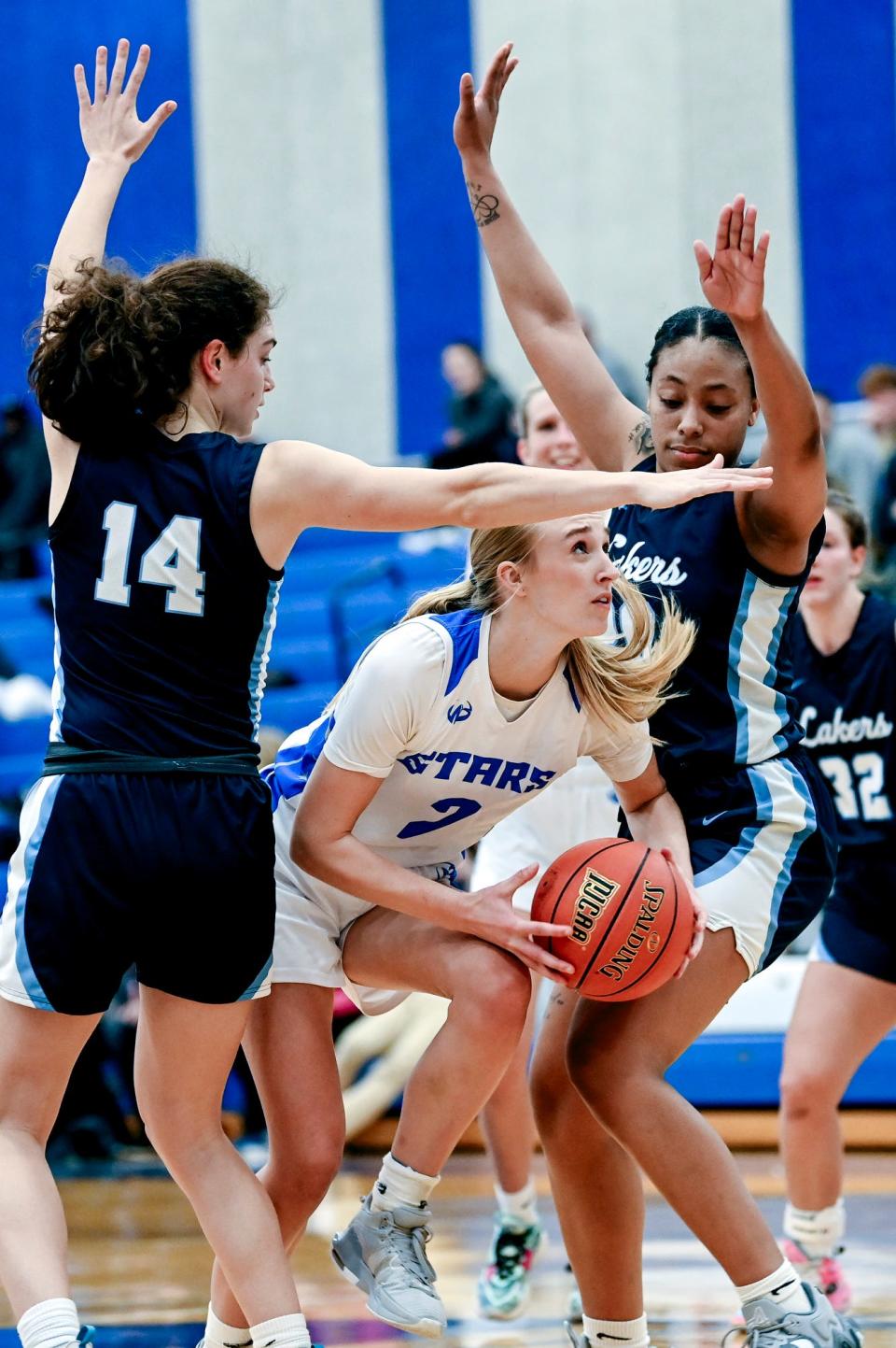 Lansing Community College's Ellie Humble, center, scores between Mid Michigan College's Chloe Watson, left, and Terre'ya Moore during the fourth quarter on Tuesday, Dec. 19, 2023, in Lansing.