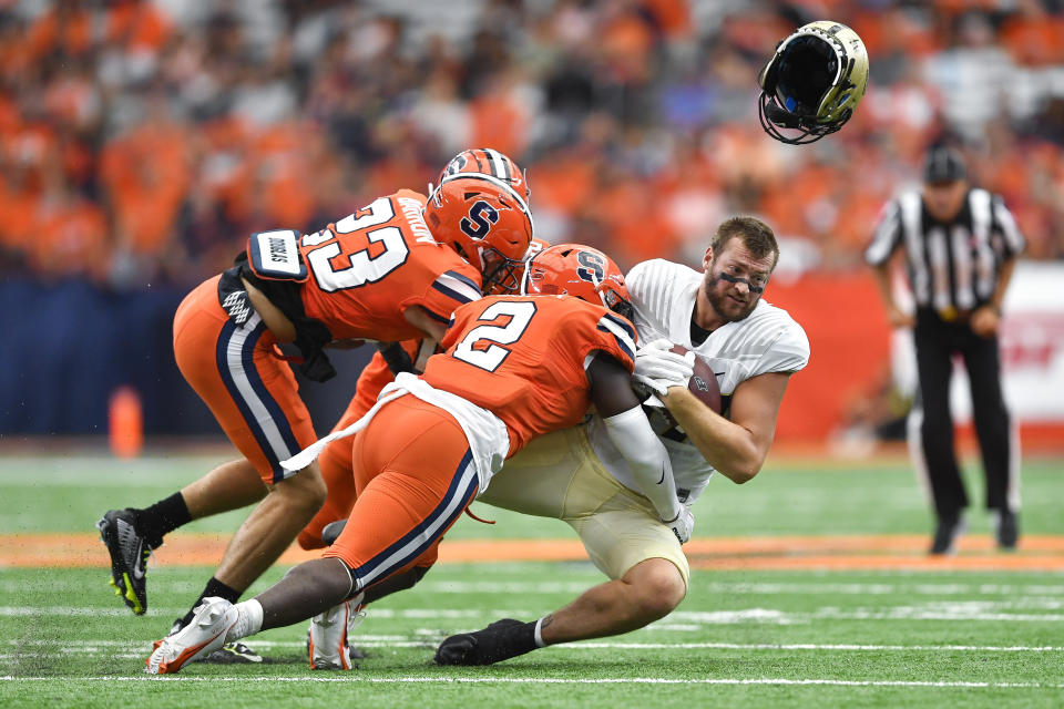 FILE - Purdue tight end Payne Durham, right, loses his helmet while being tackled by Syracuse linebacker Marlowe Wax (2) and defensive back Justin Barron (23) during the first half of an NCAA college football game in Syracuse, N.Y., Saturday, Sept. 17, 2022. Syracuse’s defense, which finished in the top-20 nationally last year, returns seven starters. (AP Photo/Adrian Kraus, File)