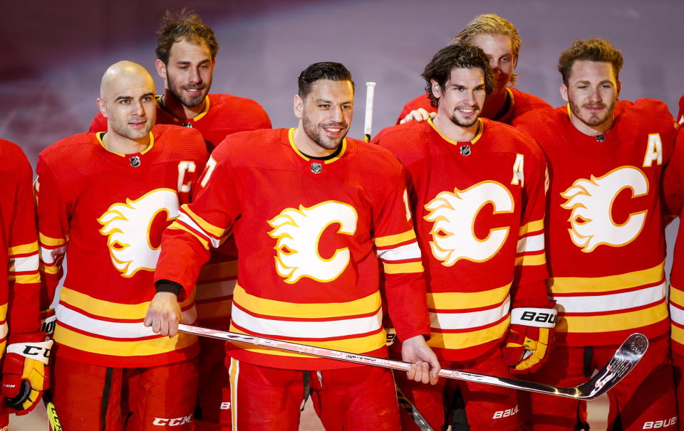 Calgary Flames' Milan Lucic, center, holds a silver stick as he poses with his teammates celebrating his 1000th NHL game before facing the Ottawa Senators, in Calgary, Alberta, Monday, April 19, 2021. (Jeff McIntosh/The Canadian Press via AP)