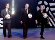FIFA General Secretary Joseph Blatter (R) kicks a ball as he walks off the stage with FIFA President Dr. Joao Havelange (C) and World Cup USA 1994 Chairman Alan Rothenberg, following the unveiling of the official ball to be used in the World Cup in the U.S., December 17, 1993. REUTERS/Gary Hershorn/File photo
