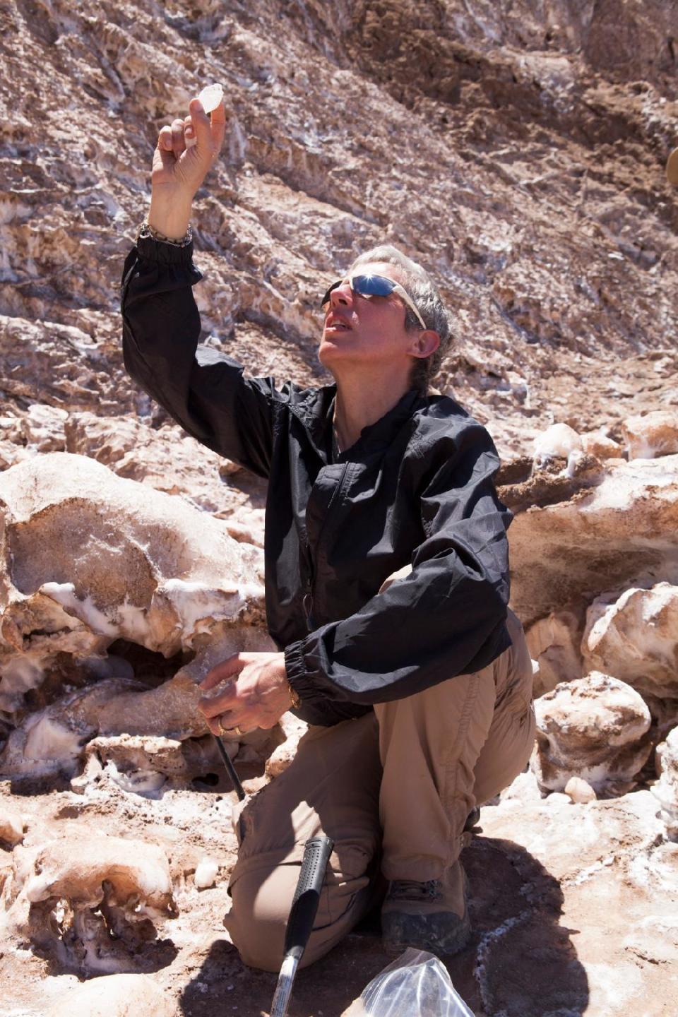 a woman with cropped silver hair in a rocky desert canyon