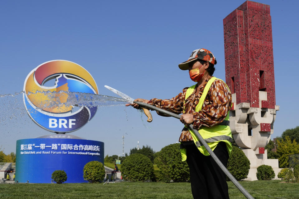 A gardener waters the grass near the logo for the Belt and Road Forum in Beijing, Monday, Oct. 16, 2023. China's Belt and Road Initiative looks to become smaller and greener after a decade of big projects that boosted trade but left big debts and raised environmental concerns. (AP Photo/Ng Han Guan)