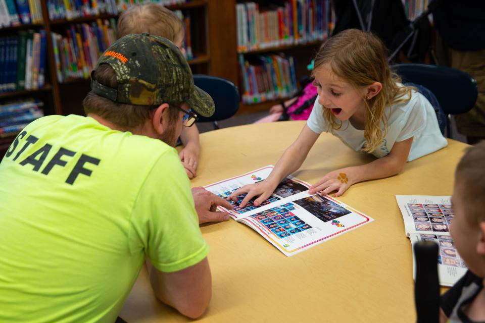 Former Warren Elementary School student Edward Bonczynski, left, shows his daughter Tiffany a photo of him in a 1995 Warren yearbook on Tuesday, May 14, 2024, in the school's library. The school is set to close this summer after a South Bend school board vote last year.