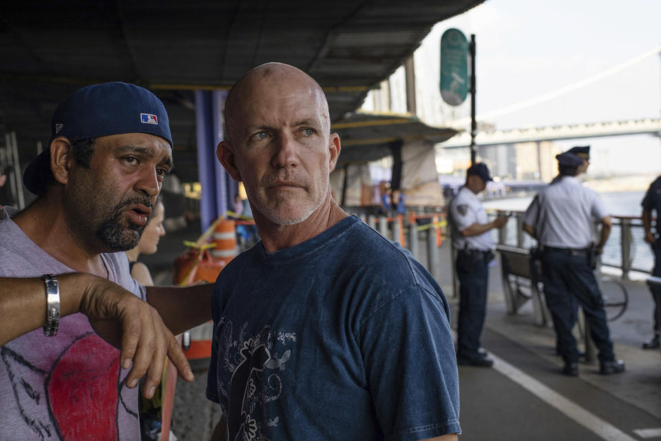 Monte Campbell, of Stillwater, Okla., right, stands under the Brooklyn Bridge in Manhattan after jumping into New York’s East River to rescue a baby floating in the water, Sunday, Aug. 5, 2018. The baby was later pronounced dead and authorities are investigating. No parent or guardian was present at the scene and the child showed no signs of trauma, police said. (AP Photo/Robert Bumsted)