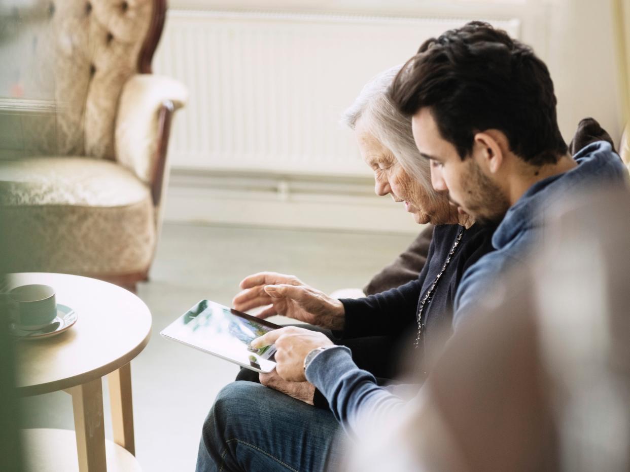 Caretaker and senior woman using digital tablet at nursing home