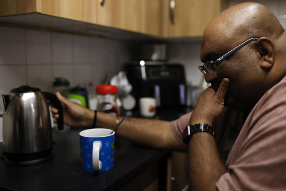 Thirugnanam Sureshan, 50, whose disabilities require round-the-clock care, waits for his kettle to boil as he discusses concerns about cost of living increases at his home in Bexhill, East Sussex, England, Wednesday, Nov. 9, 2022. Mr. Sureshan is cutting down on hot drinks like tea – a symbol of comfort in the U.K. – after his monthly electricity bill almost doubled over the past year. (AP Photo/David Cliff)