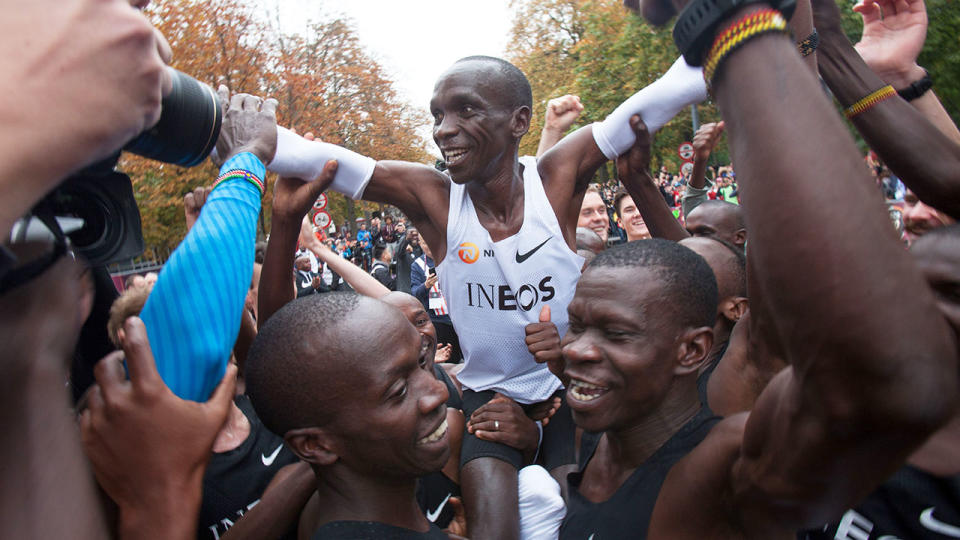 Eliud Kipchoge, pictured here being carried in triumph after crossing the finish line.