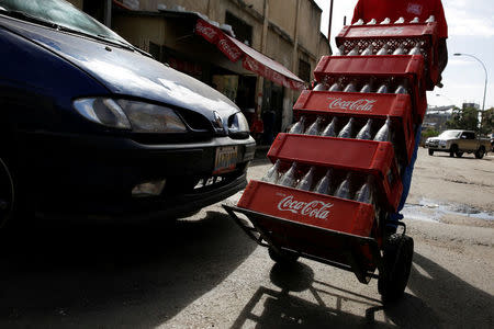 A worker pushes a dolly loaded with cases of empty Coca-Cola bottles in Caracas, Venezuela May 24, 2016. REUTERS/Carlos Garcia Rawlins