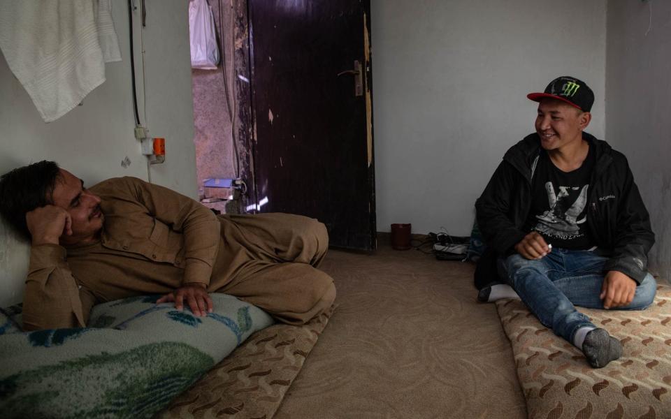 Mohammed Ali Qasimi, 27 (right) sits on his thin mattress in the room he shares with a friend - another man deported from Sweden - Stefanie glinski