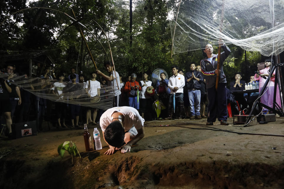 Family members and relatives pray at the entrance of Tham Luang cave while rescue personnel conduct operations to find the missing members of the children's football team along with their coach at the cave in Khun Nam Nang Non Forest Park in Chiang Rai province on June 26, 2018.