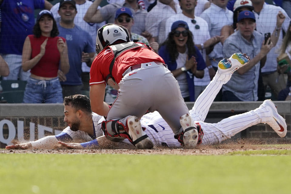 Chicago Cubs' Nick Madrigal, left, is tagged out by Cincinnati Reds catcher Tyler Stephenson, top, during the ninth inning of a baseball game Friday, May 31, 2024, in Chicago. (AP Photo/David Banks)