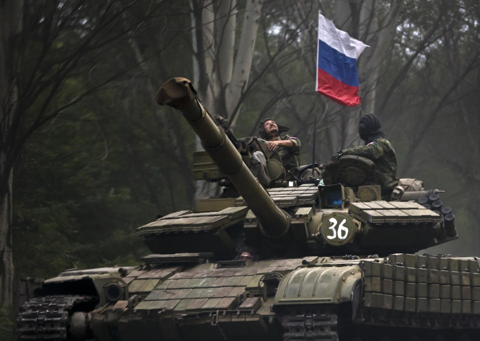 FILE - A pro-Russian rebel looks up while riding on a tank flying Russia's flag, on a road east of Donetsk, eastern Ukraine, July 29, 2015. Amid fears of a Russian invasion of Ukraine, tensions have also soared in the country’s east, where Ukrainian forces are locked in a nearly eight-year conflict with Russia-backed separatists. A sharp increase in skirmishes on Thursday raised fears that Moscow could use the situation as a pretext for an incursion. (AP Photo/Vadim Ghirda, File)