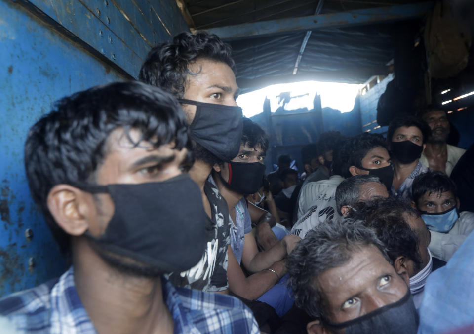 Migrant workers who were traveling in a truck to return to their home state of Uttar Pradesh are detained by police in Mumbai, India, Saturday, May 9, 2020. Locking down the country's 1.3 billion people has slowed down the spread of the virus, but has come at the enormous cost of upending lives and millions of lost jobs. (AP Photo/Rajanish Kakade)