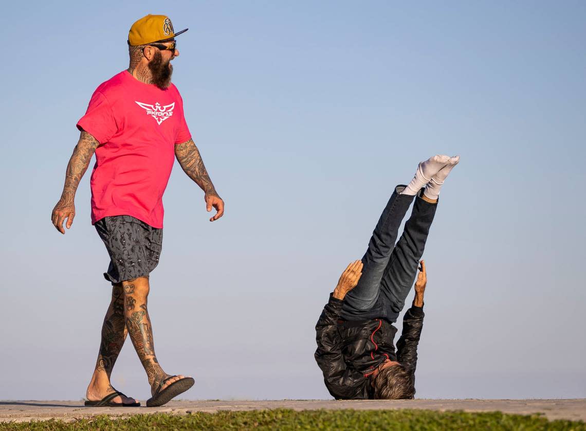 Nelson David Martinez, right, practices Hatha yoga poses as people visit South Pointe Park on Monday, Feb. 27, 2023, in Miami Beach, Florida.