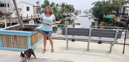 Terri Metter, 50, and her Boston Terrier Nikki stand in front of a debris-filled canal in the RV park where she has been living in a FEMA trailer since November 2017, in Marathon, Florida, U.S., June 10, 2018. REUTERS/Zach Fagenson