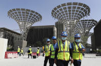 In this Oct. 8, 2019, photo, technicians walk at the three thematic districts at the under construction site of the Expo 2020 in Dubai, United Arab Emirates. (AP Photo/Kamran Jebreili)