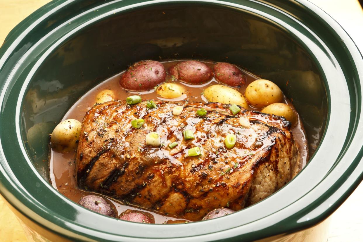 A good looking roast in a crock pot surrounded by potatos