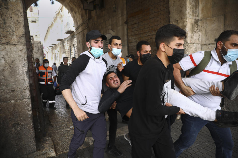 Palestinos evacuando a un manifestante herido durante choques con las fuerzas de seguridad israelíes en la Puerta del León, en la ciudad vieja de Jerusalén, el lunes 10 de mayo de 2021. La policía israelí chocó con manifestantes palestinos en un disputado lugar de culto en Jerusalén, dentro de una escalada de tensiones en la ciudad. (AP Foto/Oded Balilty)