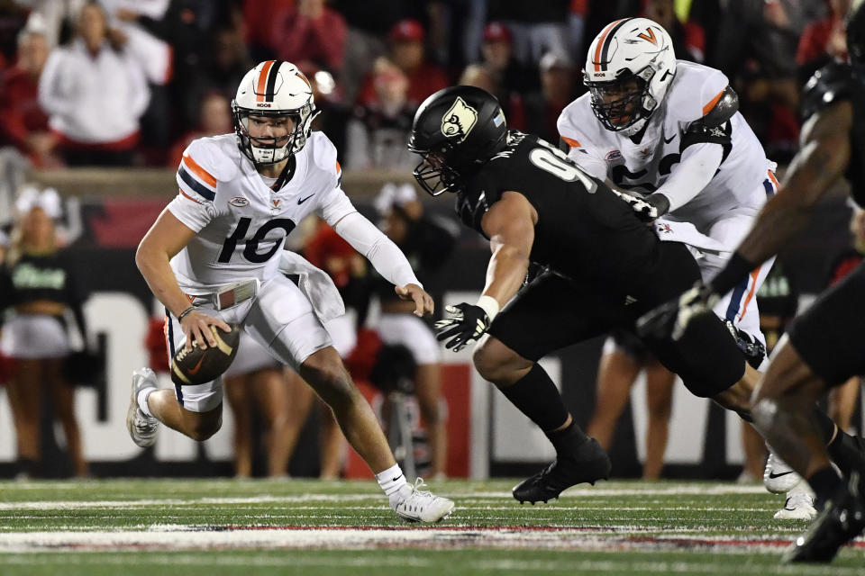 Virginia quarterback Anthony Colandrea (10) attempts to avoid the tackle attempt from Louisville defensive lineman Mason Reiger (95) during the first half of an NCAA college football game in Louisville, Ky., Thursday, Nov. 9, 2023. (AP Photo/Timothy D. Easley)