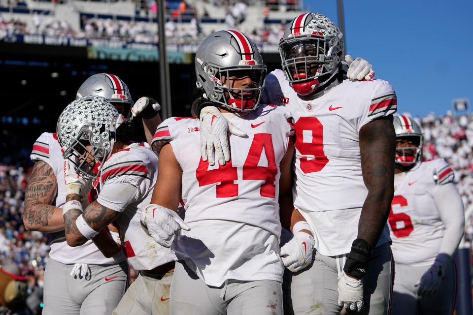 Ohio State defensive end J.T. Tuimoloau (44) celebrates his pick-six touchdown with fellow defensive lineman Zach Harrison (9).