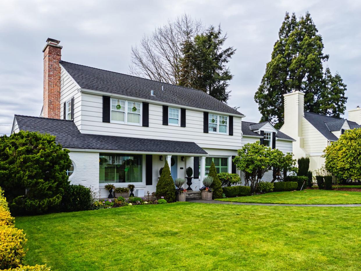 Photo of a white American colonial style home exterior on a bright overcast spring day