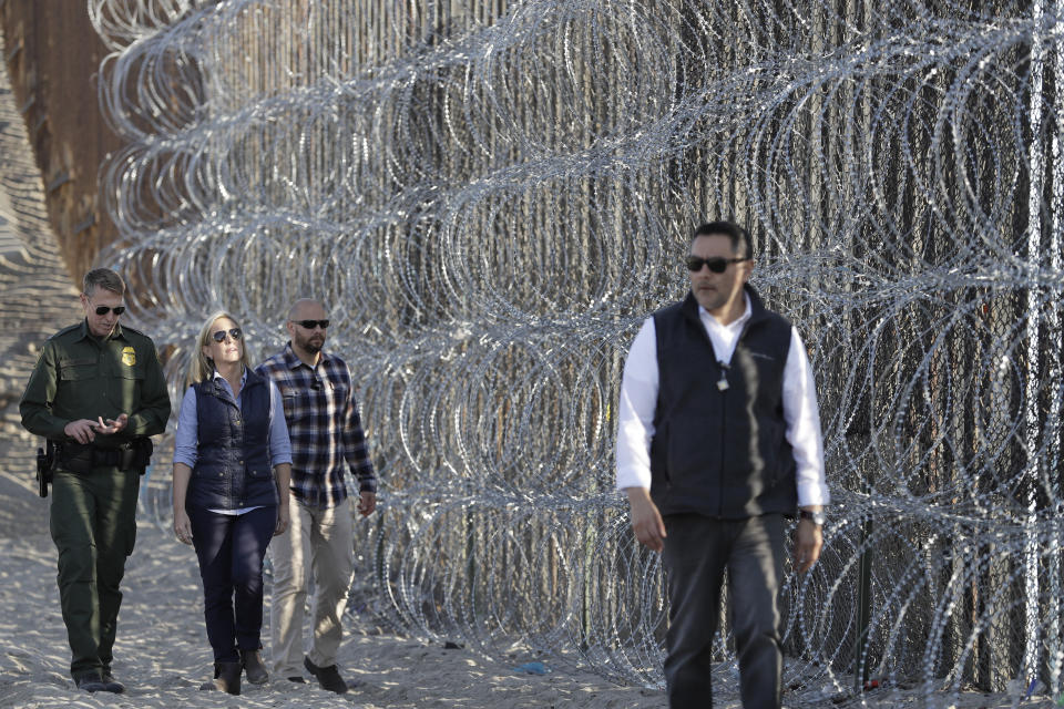 Secretary of Homeland Security Kirstjen Nielsen, center in blue shirt, walks with San Diego Sector Border Patrol chief Rodney Scott, left, next to a section of the border wall fortified with razor wire Tuesday, Nov. 20, 2018, in San Diego. Nielsen says an appeal will be filed on the decision by a judge to temporarily bar the Trump administration from refusing asylum to immigrants who cross the southern border illegally. Speaking in San Diego, Nielsen said it would be filed as soon as possible. (AP Photo/Gregory Bull)