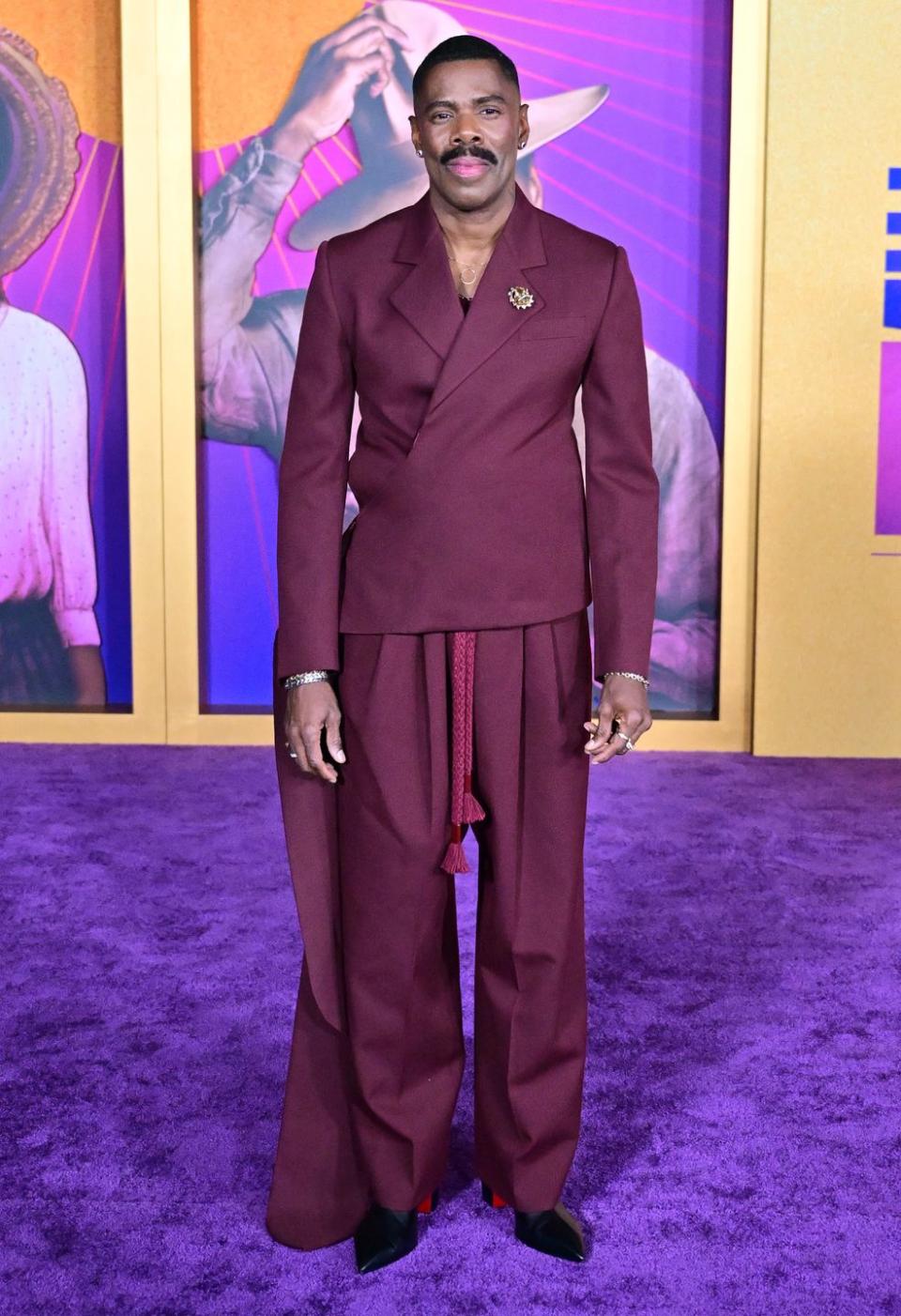 colman domingo, an actor with a thick moustache, wearing a purple suit and posing on a purple carpet at the color purple 2023 premiere