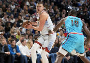 Denver Nuggets center Nikola Jokic, left, looks to pass the ball as Phoenix Suns center Bismack Biyombo defends in the first half of an NBA basketball game, Sunday, Dec. 25, 2022, in Denver. (AP Photo/David Zalubowski)