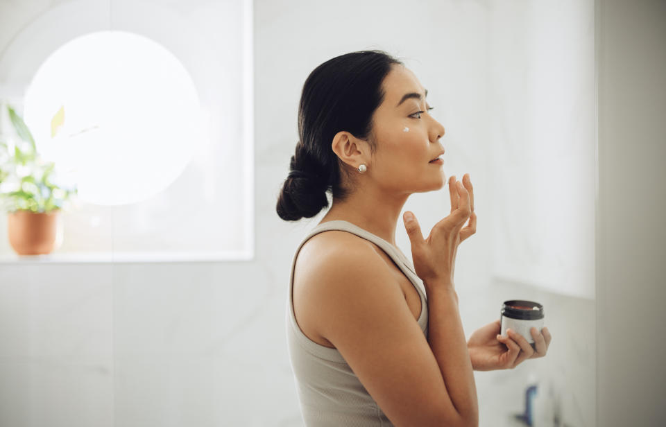 A woman applying face cream