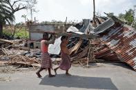 Residents carry tin sheets salvaged from the rubble of a damaged house in the aftermath of Cyclone Amphan, in South 24 Parganas district