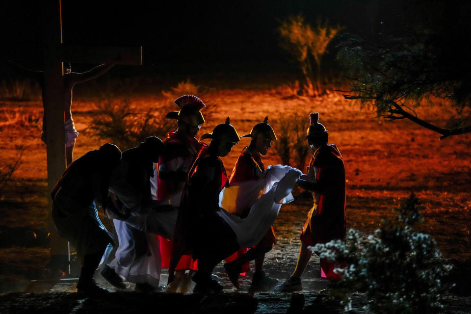 Devotos caracterizados como soldados se llevan a Daniel Hernández, que interpreta a Jesucristo, envuelto en un sudario blanco tras bajarlo de la cruz, en una representación del Via Crucis con motivo de la Semana Santa, en Colina, Chile, el 29 de marzo de 2024. La Semana Santa conmemora los últimos días de la vida de Jesús, según la Biblia, incluyendo su crucifixión el Viernes Santo y su resurrección en el Domingo de Pascua. (AP Foto/Esteban Félix)