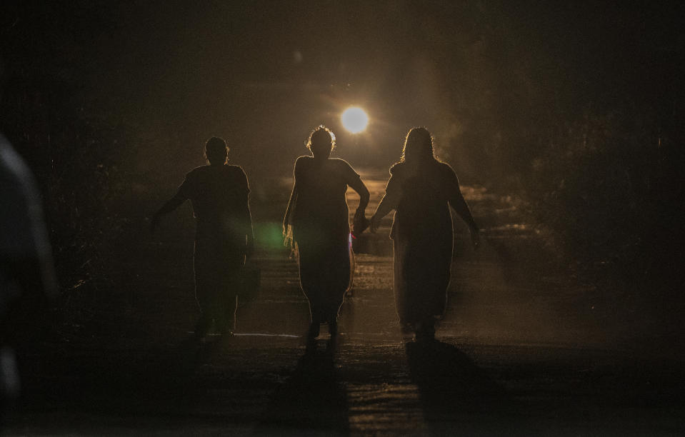 Women return home after relieving themselves in the open in Aarey Colony, which borders the south end of Sanjay Gandhi National Park, in Mumbai, India, Tuesday, April 5, 2022. Los Angeles and Mumbai, India are the world’s only megacities of 10 million-plus where large felines breed, hunt and maintain territory within urban boundaries. Long-term studies in both cities have examined how the big cats prowl through their urban jungles, and how people can best live alongside them. (AP Photo/Rafiq Maqbool)