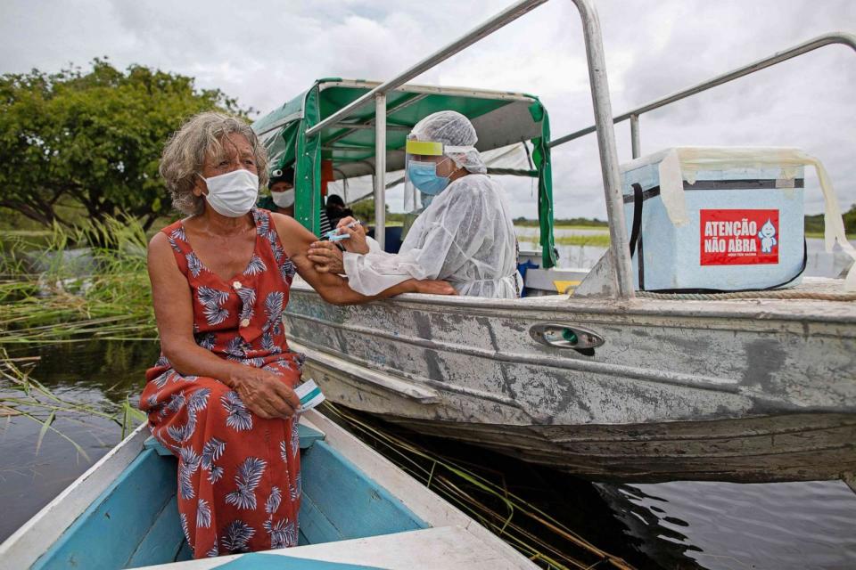 PHOTO: Olga D'arc Pimentel, 72, is vaccinated by a health worker with a dose of the Oxford-AstraZeneca COVID-19 vaccine in the Nossa Senhora Livramento community on the banks of the Rio Negro near Manaus, Brazil on Feb. 9, 2021. (Michael Dantas/AFP via Getty Images)