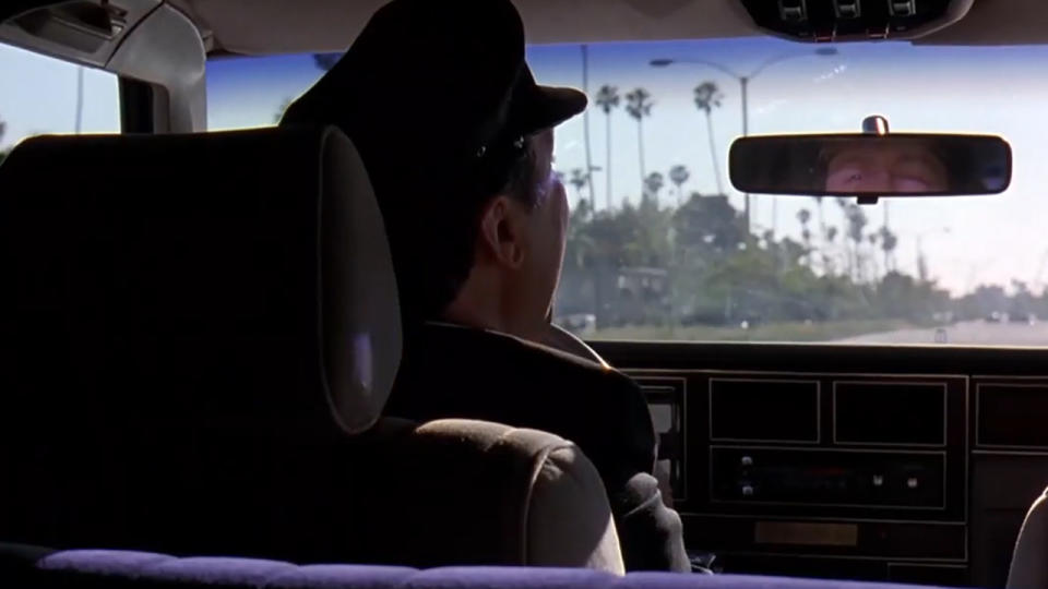 Dom Irrera looking back through a rear view mirror as he drives in The Big Lebowski