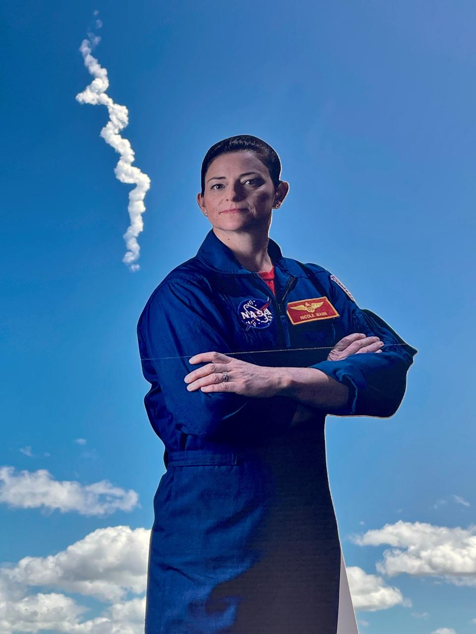 Crew-5's SpaceX Falcon 9 rocket exhaust plume swirls in the sky above a cardboard cutout of mission commander Nicole Mann during a Wednesday watch party at The Space Bar in Titusville.