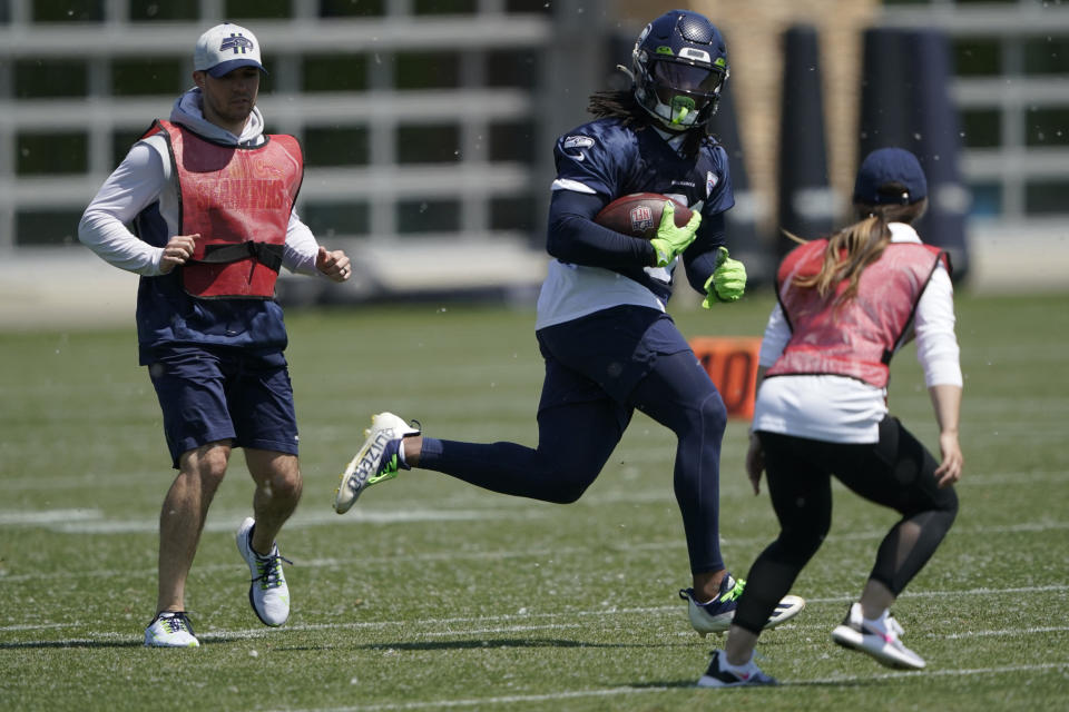 Amanda Ruller, right, who is currently working as an assistant running backs coach for the NFL football Seattle Seahawks through the league's Bill Walsh Diversity Fellowship program, runs a drill with DeeJay Dallas, center, during NFL football practice May 31, 2022 in Renton, Wash. Ruller's job is scheduled to run through the Seahawks' second preseason game in August. (AP Photo/Ted S. Warren)