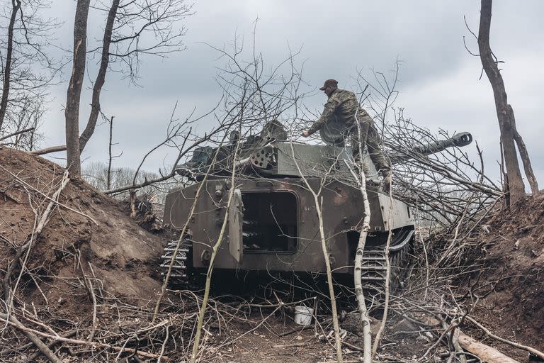 Un soldado ucraniano cubre un vehículo armado con ramas, en Donbass