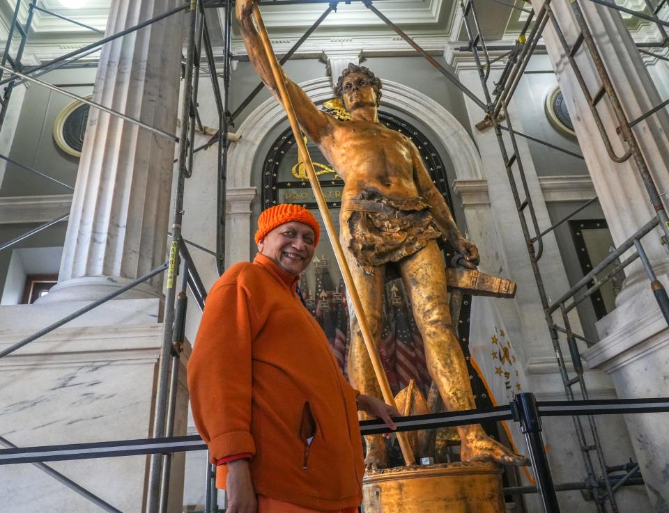 Swami Yogatmananda of the Vedanta Society of Providence poses with the Independent Man before the statue undergoes restoration. Visitors lined up at the State House on Friday and signed a guest book as they viewed the icon.