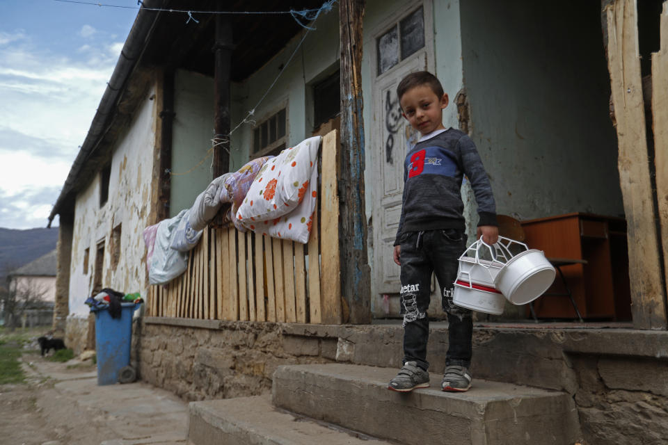 Milan Bastyur, a 4 year old Hungarian Roma child, holds containers as he goes to pick up food for lunch in Bodvaszilas, Hungary, Monday, April 12,2021. Many students from Hungary's Roma minority do not have access to computers or the internet and are struggling to keep up with online education during the pandemic. Surveys show that less than half of Roma families in Hungary have cable and mobile internet and 13% have no internet at all. (AP Photo/Laszlo Balogh)