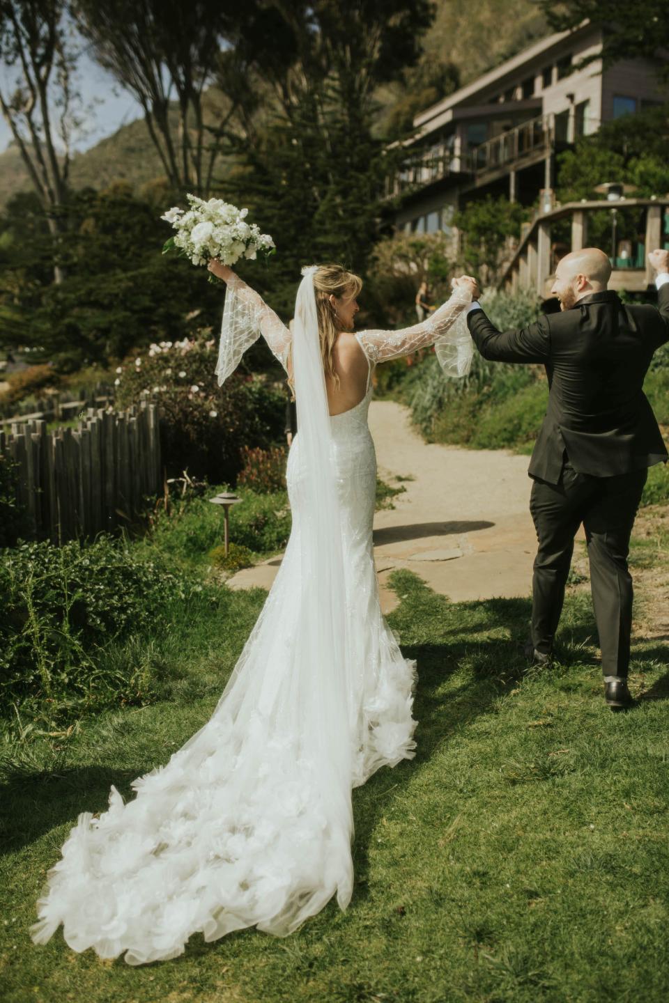 A bride and groom raise their arms in triumph as they leave their wedding ceremony.