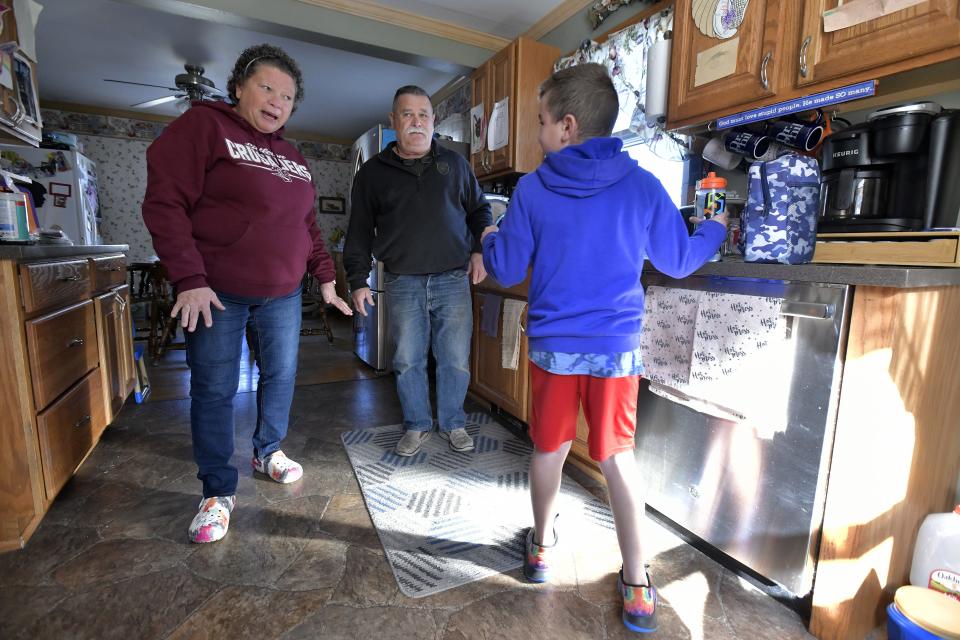 David Miller of Littleton, N.H., 61, looks on as his wife Tina Miller, left, and  Kah'leal Oliver, 8, center, one of three children that the Millers are caring for, prepare to go to a Sunday afternoon soccer game and David goes to work.