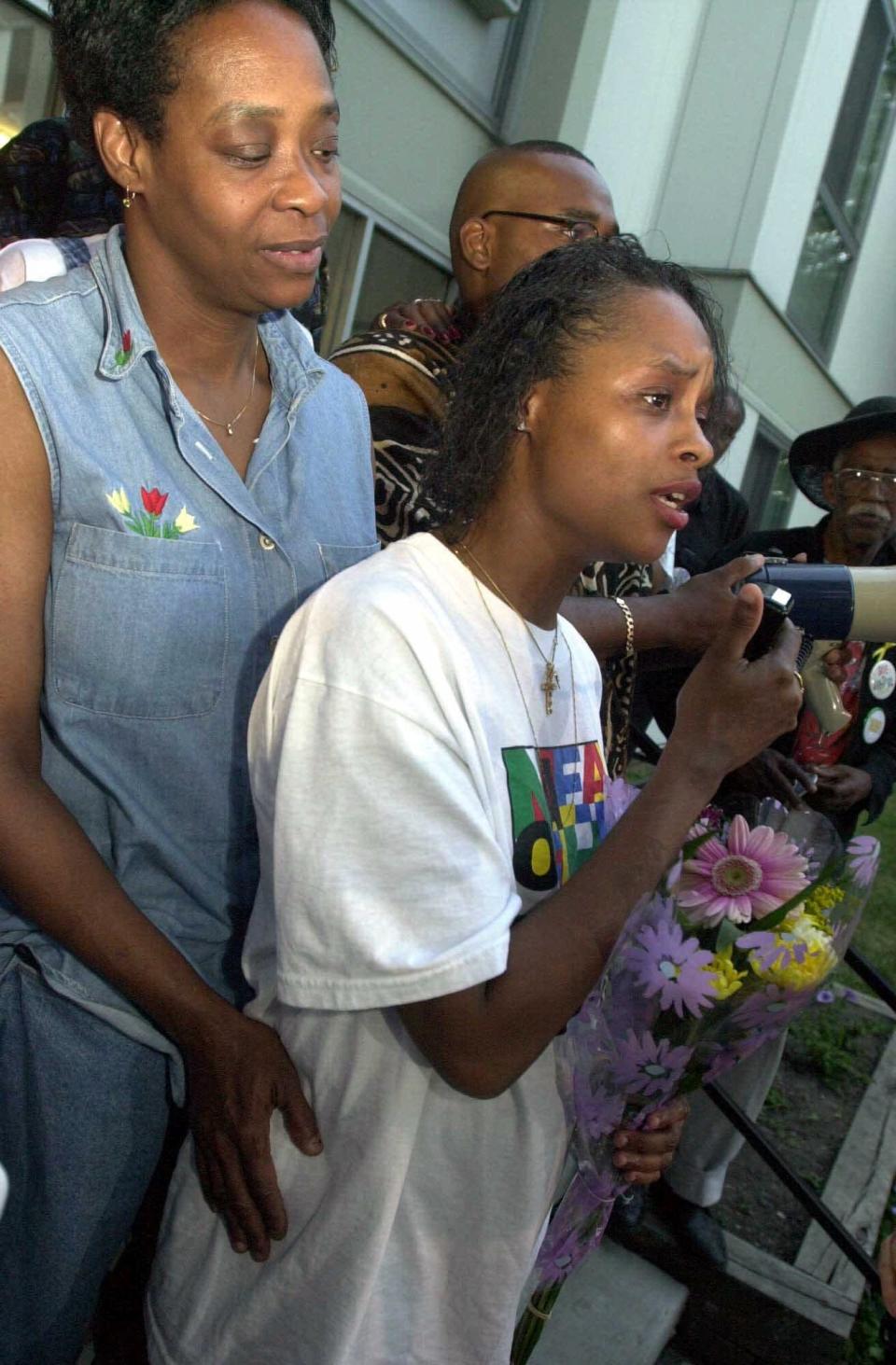 Tracey Bradley, right, mother of two missing girls, Tionda, 10, and Diamond, 3, speaks to the crowd gathered for the nightly prayer vigil outside their apartment complex July 14, 2001, in Chicago. She is held by her mother, Mary Bradley-Hunt.