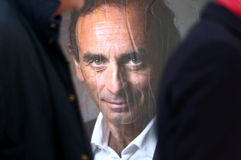 People walk past a poster in support of French far-right commentator Eric Zemmour in Paris