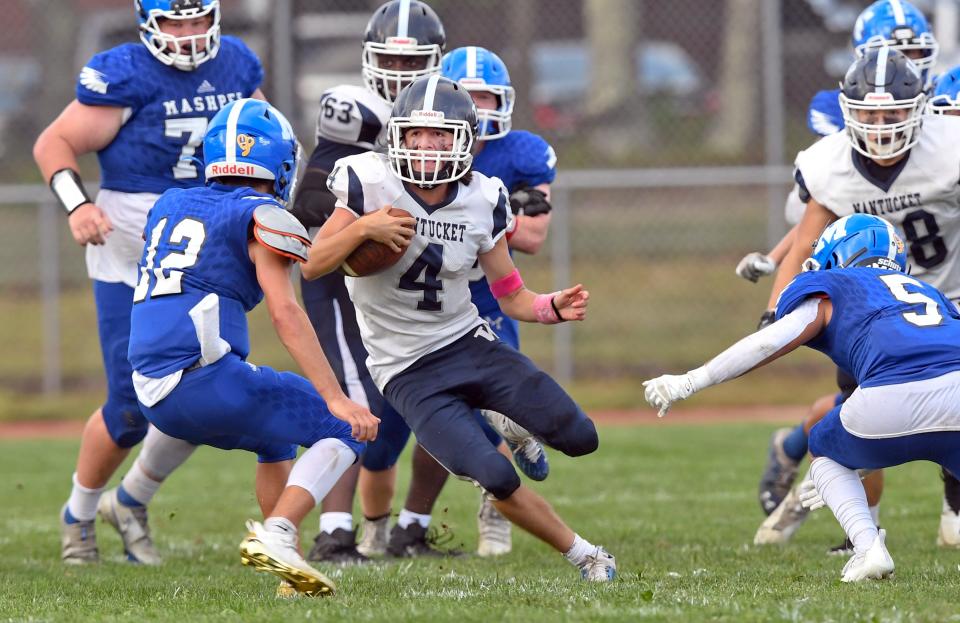 Nantucket quarterback Carlos Aguilar attempts to avoid the tackle by Brady Johnston (12) and Aiden Cuozzo of Mashpee.