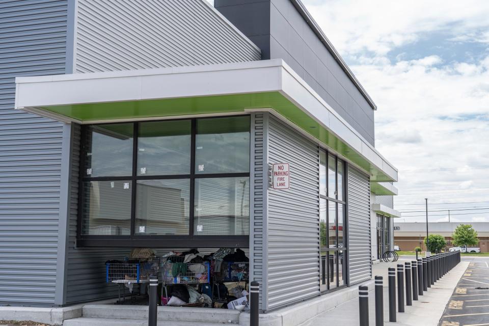 Carts with clothes and personal items are seen in an outdoor section of an undeveloped Amazon Fresh store in Roseville on Tuesday, May 28, 2024. The store's exterior is near finished but the inside as seen through the front windows is empty.