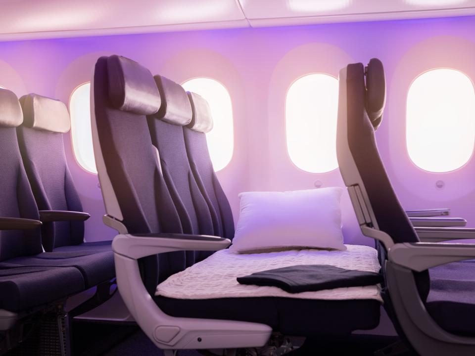 Traditional airline seats with the arm rests folded away enables passengers to lay a mattress across the seats.