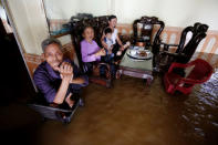A family sits in their flooded house after heavy rainfall caused by tropical storm Son Tinh in Ninh Binh province, Vietnam. REUTERS/Kham