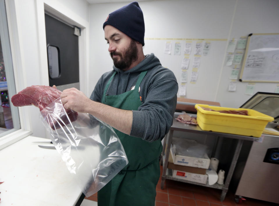 In this Dec. 11, 2013 photo James Peisker places a beef top round in a bag in which the meat will be marinated for six days as part of the process of preparing the "spiced round," a Christmastime beef specialty, at the Porter Road Butcher in Nashville, Tenn. The cured top round, traditionally laced with strands of lard mixed with a variety of spices including cinnamon, allspice and clove, was popularized by the city's German and English meatpackers after the Civil War. (AP Photo/Mark Humphrey)