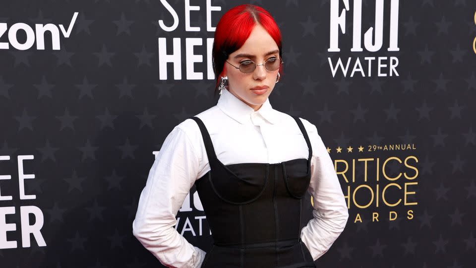 Billie Eilish wore a Thom Browne look comprising a white floor-length shirtdress beneath a little black dress with structured bodice. - Michael Tran/AFP/Getty Images