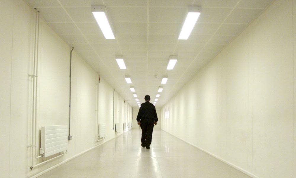 A security officer patrols a corridor in an immigration removal centre. 